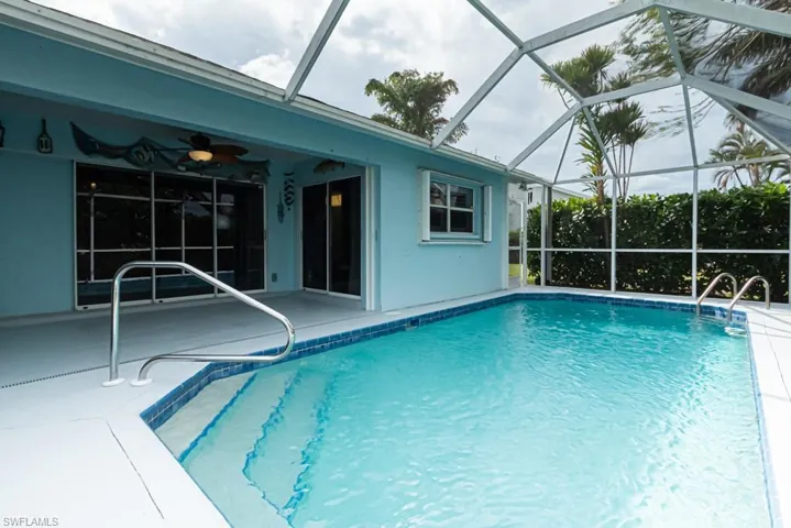 View of pool with a patio, ceiling fan, and glass enclosure