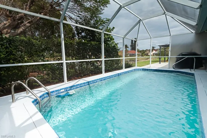 View of pool with a water view, a patio area, and glass enclosure