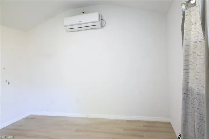 Unfurnished room featuring light wood-style flooring and a wall unit AC