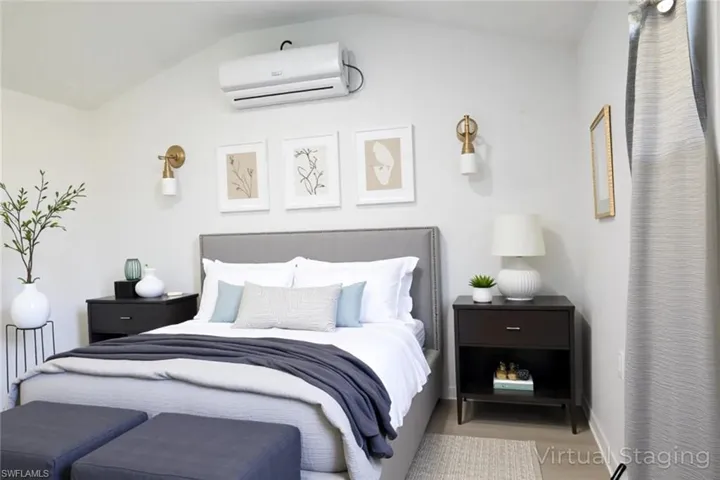 Bedroom featuring an AC wall unit and vaulted ceiling