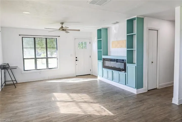 Unfurnished living room with dark wood-type flooring and ceiling fan