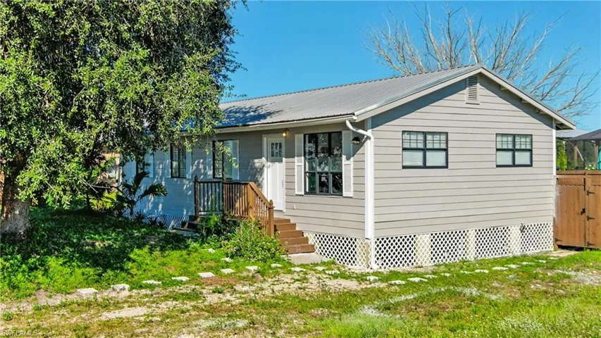 View of front facade with a metal roof, a front yard, and crawl space