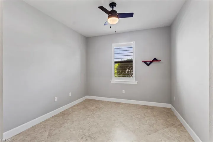 Spare room featuring a ceiling fan and baseboards