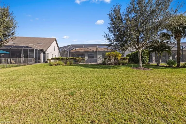 View of grassy yard featuring a sunroom and glass enclosure