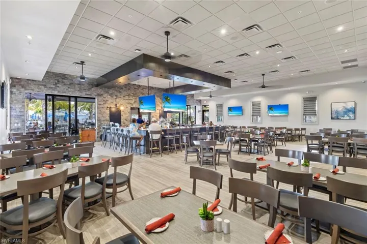 Dining space featuring a ceiling fan, a high ceiling, a drop ceiling, wood finished floors, and plenty of natural light