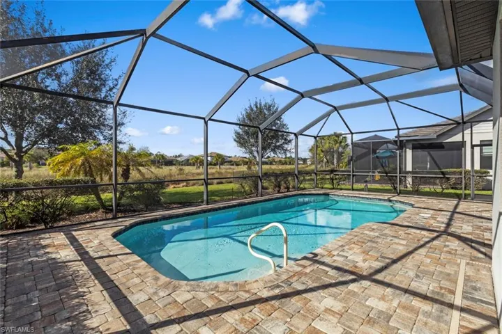 Outdoor pool with glass enclosure, a sunroom, and a patio