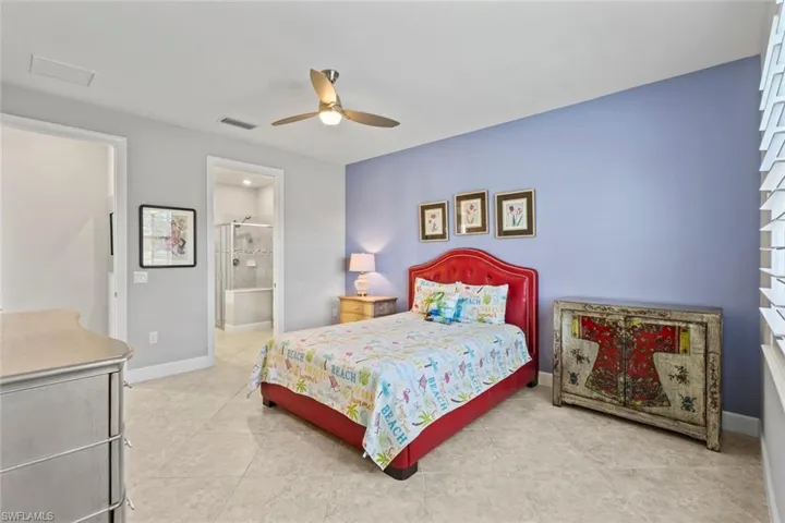 Bedroom featuring a ceiling fan, light tile patterned flooring, and ensuite bath