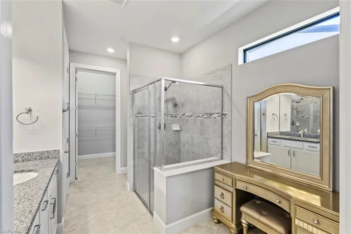 Bathroom featuring vanity, a walk in closet, a shower stall, and recessed lighting