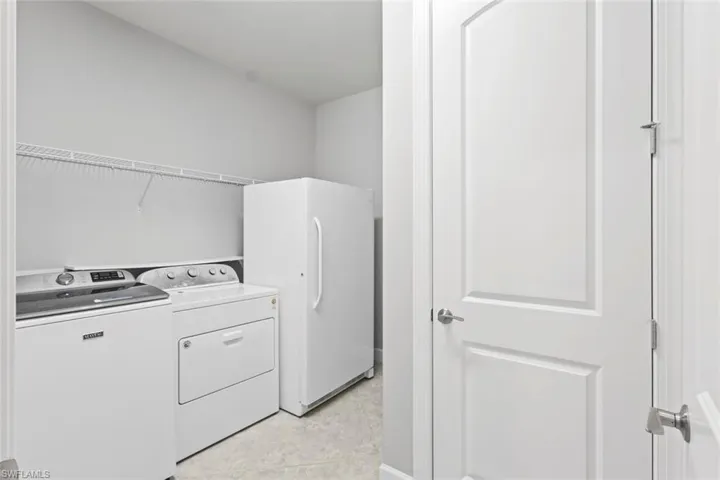 Washroom featuring washer and clothes dryer and light tile patterned flooring