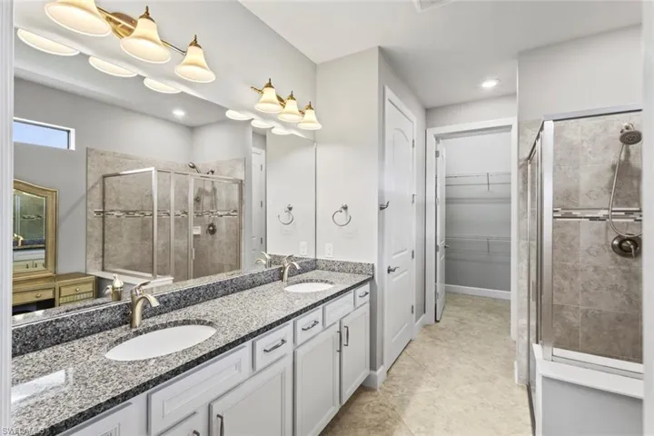 Bathroom featuring a stall shower, double vanity, and a walk in closet