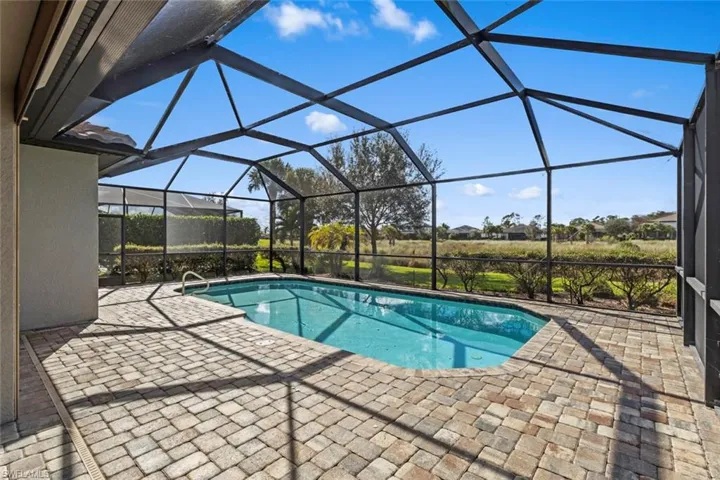 Outdoor pool featuring a sunroom, a patio, and glass enclosure