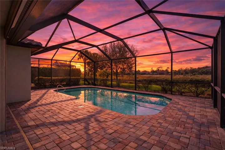 Outdoor pool with a sunroom, glass enclosure, and a patio area
