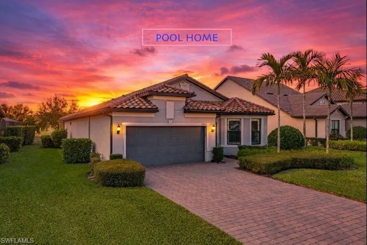 Mediterranean / spanish home featuring stucco siding, decorative driveway, a lawn, a garage, and a tiled roof