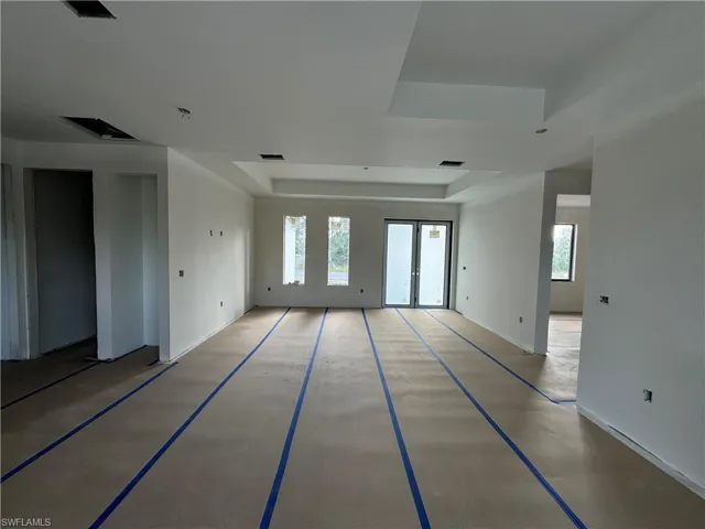 Empty room with french doors, concrete flooring, and a tray ceiling