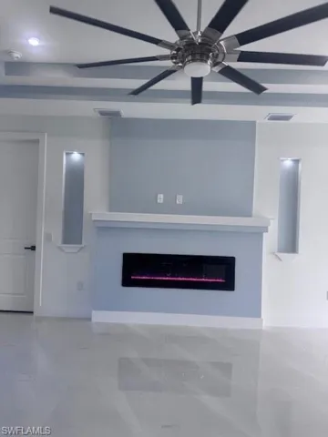 Unfurnished living room with a glass covered fireplace, a ceiling fan, and marble finish floors