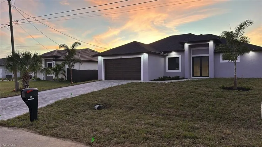 View of front of house featuring a garage and a lawn
