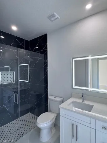 Bathroom with vanity, toilet, a shower with door, and a textured ceiling