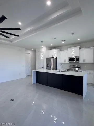 Kitchen featuring white cabinetry, sink, a center island, stainless steel fridge with ice dispenser, and range