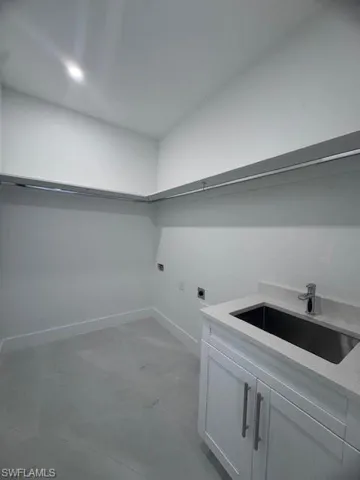 Laundry area featuring cabinets, hookup for a washing machine, electric dryer hookup, and sink
