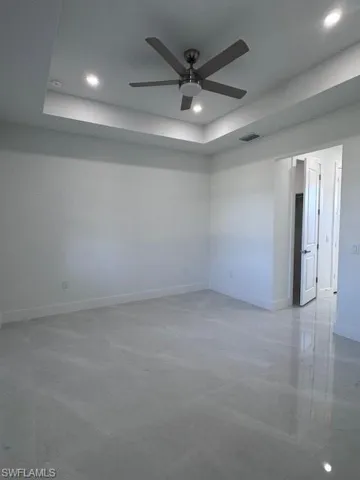 Empty room featuring a raised ceiling and ceiling fan