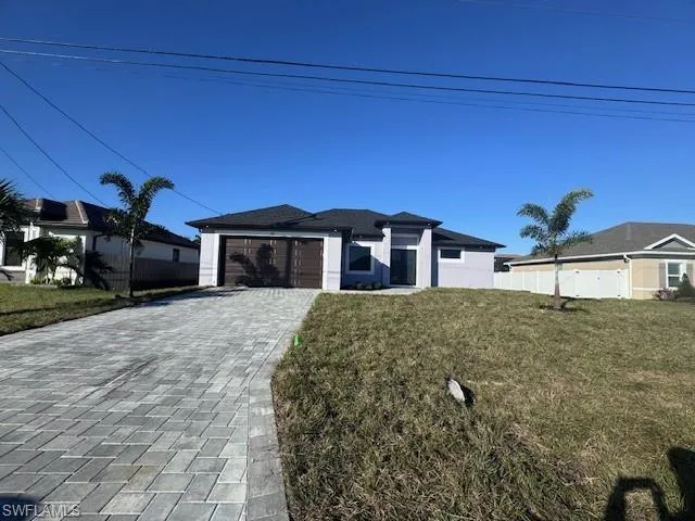 View of front of house featuring a garage and a front lawn