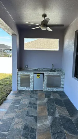 View of patio / terrace with ceiling fan, sink, and an outdoor kitchen