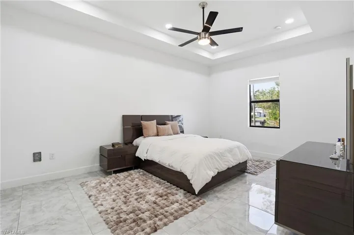 Bedroom with ceiling fan, a raised ceiling, and recessed lighting