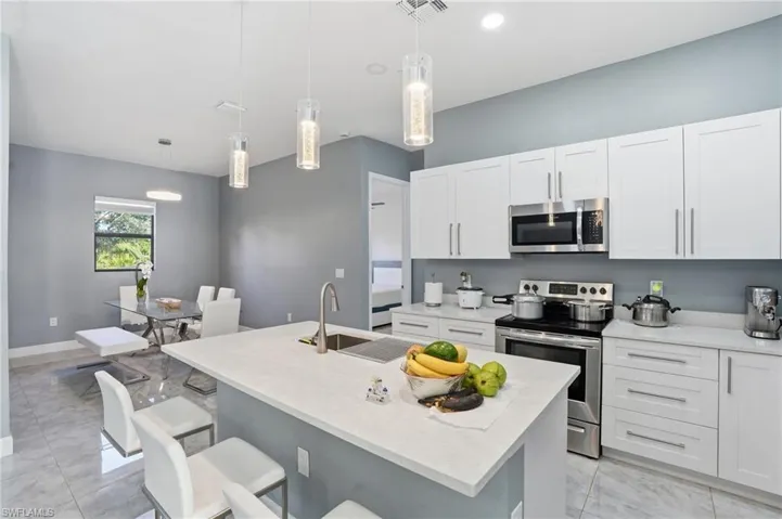 Kitchen with appliances with stainless steel finishes, hanging light fixtures, white cabinets, and recessed lighting