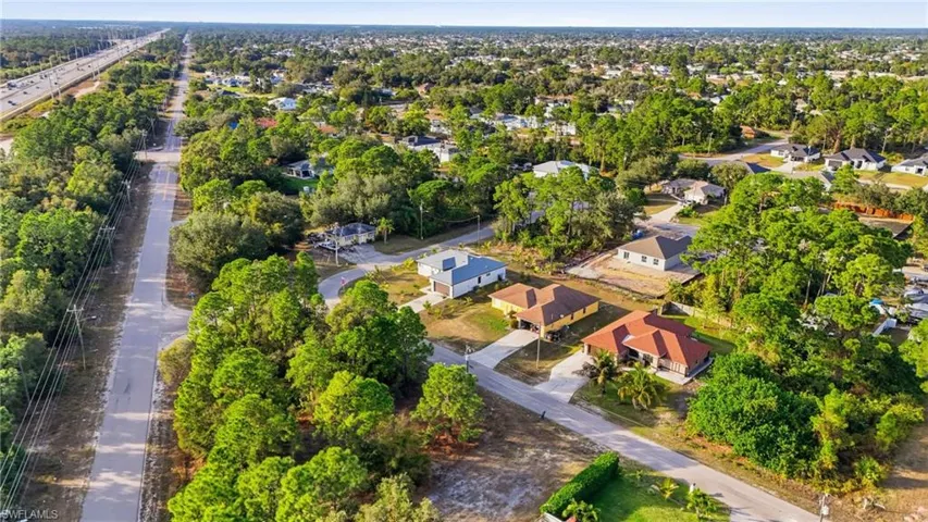 Aerial view of property and surrounding area with nearby suburban area and a tree filled landscape