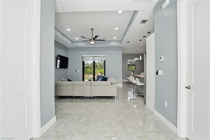 Living room with recessed lighting, a raised ceiling, and ceiling fan