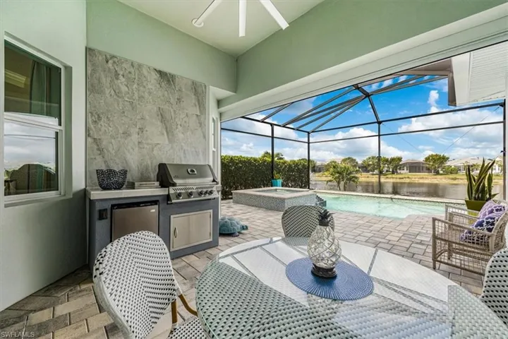 View of patio featuring a water view, area for grilling, a pool with hot tub, and ceiling fan