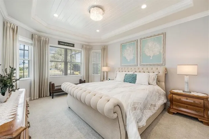 Carpeted bedroom with ornamental molding and a raised ceiling