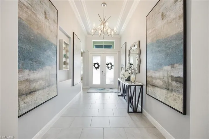 Entryway featuring ornamental molding, french doors, a notable chandelier, and light tile patterned floors