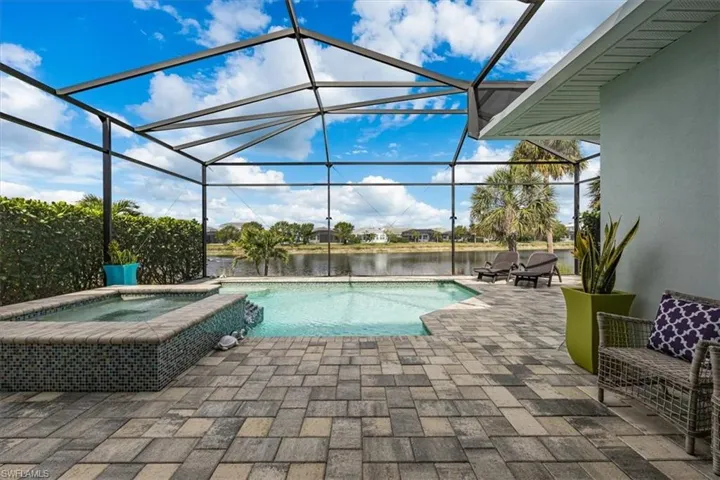 View of swimming pool with a patio, a water view, an in ground hot tub, and glass enclosure