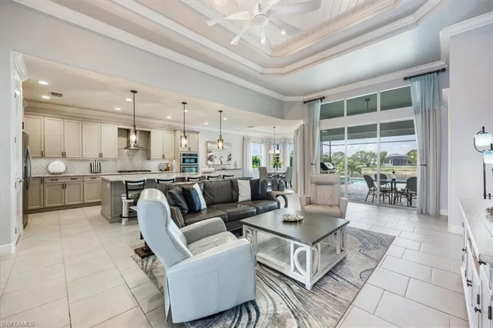 Living room featuring ceiling fan, light tile patterned floors, crown molding, and a raised ceiling