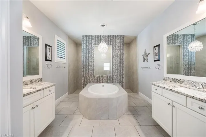 Bathroom with separate shower and tub, vanity, and an inviting chandelier