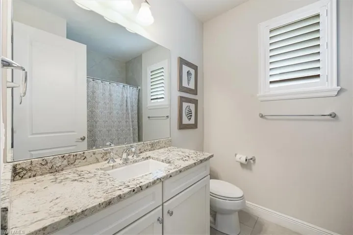 Bathroom with a shower with shower curtain, tile patterned floors, toilet, and vanity