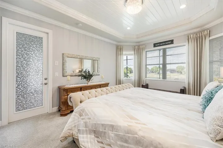 Carpeted bedroom featuring a tray ceiling, ornamental molding, access to exterior, and wooden ceiling