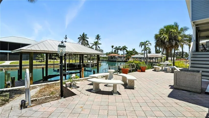 View of patio / terrace featuring boat lift, a boat dock, and a water view - Virtually Edited Image