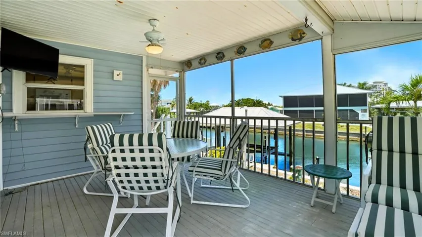 Sunroom / solarium with a water view, vaulted ceiling, and ceiling fan - Virtually Edited Image
