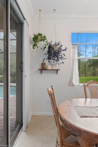 Dining room featuring crown molding, healthy amount of natural light, and light tile patterned flooring