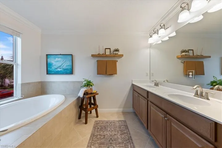 Bathroom with double vanity, a garden tub, crown molding, and tile patterned floors