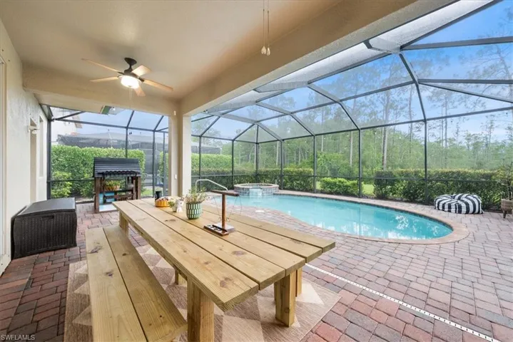 View of pool featuring a patio area, ceiling fan, glass enclosure, and a pool with connected hot tub