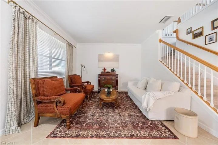 Living area featuring ornamental molding, tile patterned floors, and stairway