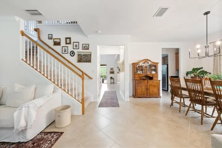Entryway featuring ornamental molding, stairway, a chandelier, and light tile patterned floors