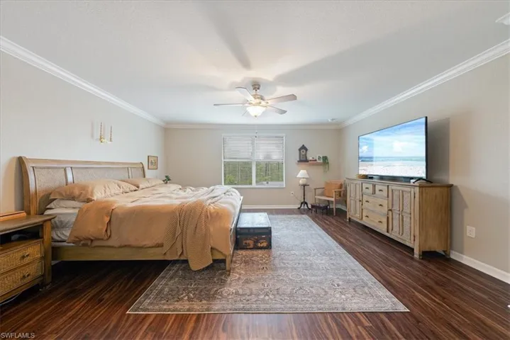 Bedroom featuring wood finished floors, crown molding, and a ceiling fan