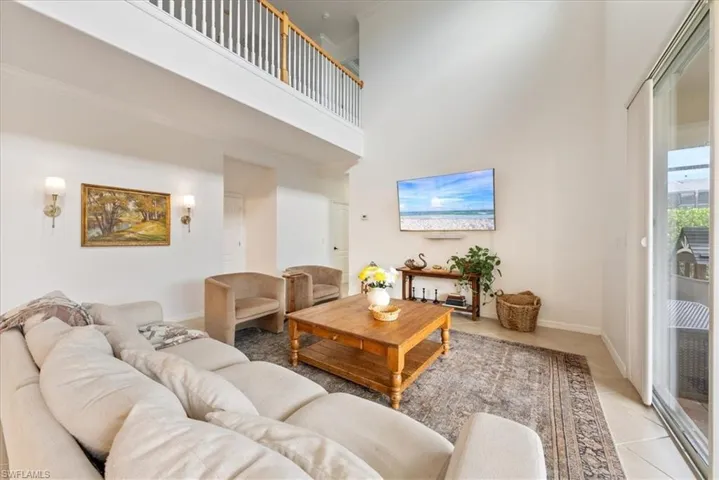 Living area featuring a high ceiling, light tile patterned flooring, and crown molding