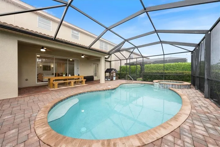 View of pool with a patio area, a ceiling fan, a pool with connected hot tub, and a lanai