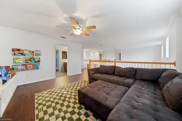 Living room with a ceiling fan, wood finished floors, and crown molding