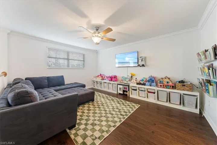 Living area with dark wood finished floors, ornamental molding, and ceiling fan